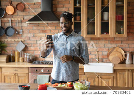 Happy biracial man talk on video call cooking at home 70583401