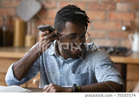 Smiling biracial man listen to audio message on smartphone Smiling biracial man listen to audio message on smartphone 70583574
