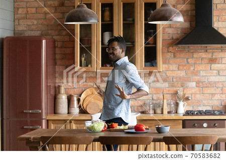 Happy biracial man dance cooking at home kitchen 70583682