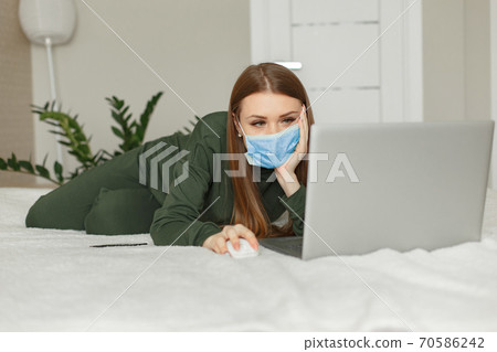 Woman sitting on a bed and uses a laptop Woman sitting on a bed and uses a laptop 70586242