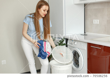 Woman uses a washing machine in the kitchen Woman uses a washing machine in the kitchen 70586256