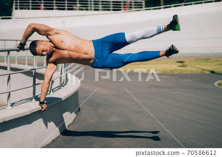 Young athletic man performs gymnastic elements - human flag. 70586612