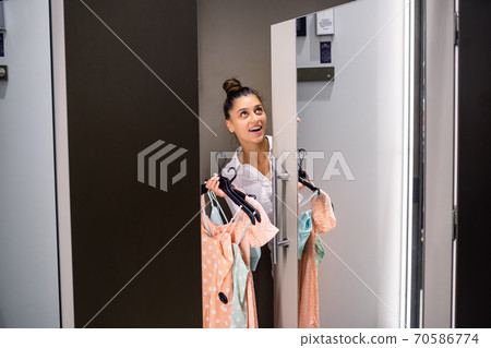 Beautiful girl with lots clothes in room background in a boutique 70586774