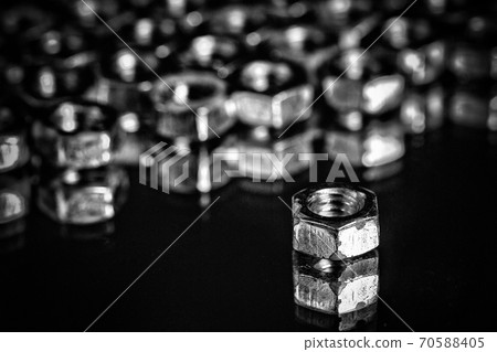 pile of silver colored nuts on a black background. 70588405