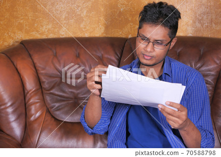 young man in casual dress sitting on sofa working from home  70588798