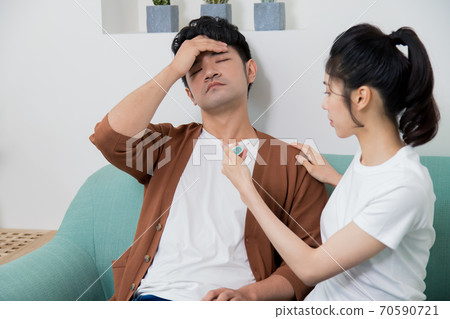 Woman takes the temperature of an uncomfortable man Woman takes the temperature of an uncomfortable man 70590721