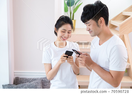 Young man and woman using smartphones indoors Young man and woman using smartphones indoors 70590728