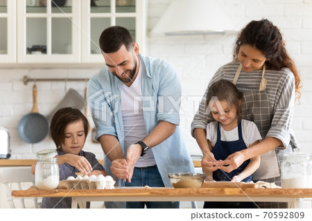 Happy mother and father with two kids baking together 70592809