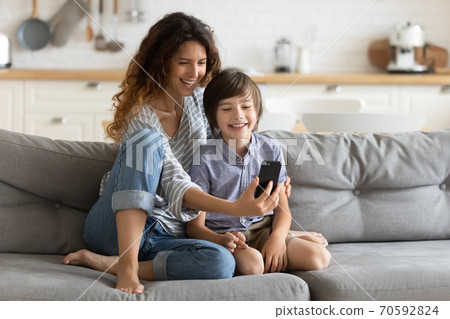 Smiling young mother and little son using phone together 70592824