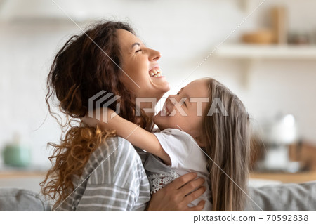 Close up overjoyed young mother and daughter hugging and laughing Close up overjoyed young mother and daughter hugging and laughing 70592838