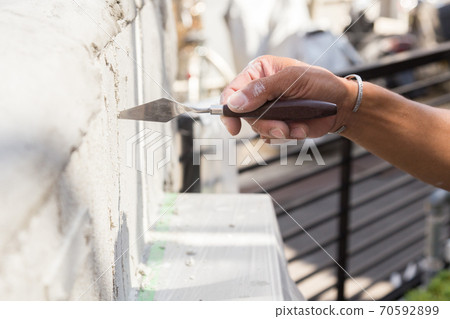 Plasterer painting the gatepost 70592899