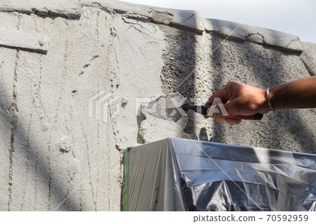 Plasterer painting the gatepost 70592959