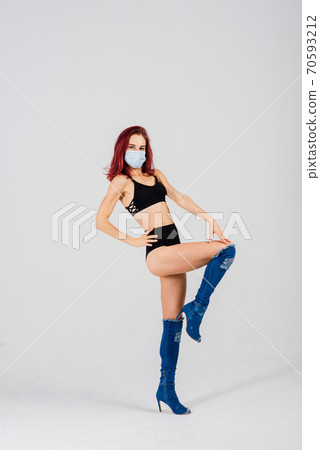 Female dancer in the styles of strip-plastic and pole dance with face mask on light background. 70593212