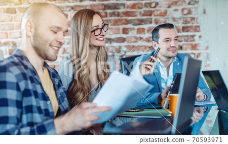 Businesspeople in startup company looking at graphs and figures Businesspeople in startup company looking at graphs and figures 70593971