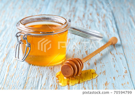 open jar of honey on a blue table, selective focus. open jar of honey on a blue table, selective focus. 70594799