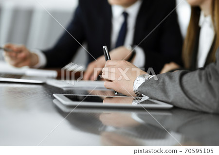 Unknown businessmen and woman sitting, using laptop computer and discussing questions at meeting in modern office, close-up Unknown businessmen and woman sitting, using laptop computer and discussing questions at meeting in modern office, close-up 70595105