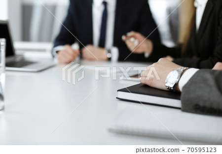 Unknown businessmen and woman sitting, working and discussing questions at meeting in modern office, close-up 70595123