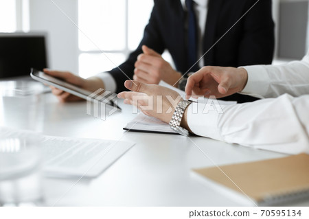 Unknown business people using tablet computer in modern office. Businessman or male entrepreneur is working with his colleague at the desk Unknown business people using tablet computer in modern office. Businessman or male entrepreneur is working with his colleague at the desk 70595134