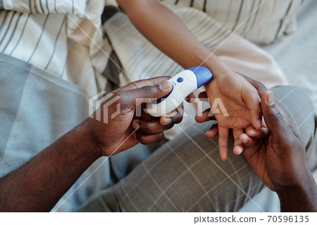 Hands of young careful father measuring body temperature of his sick little son Hands of young careful father measuring body temperature of his sick little son 70596135