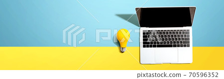 Laptop computer with a yellow light bulb Laptop computer with a yellow light bulb 70596352