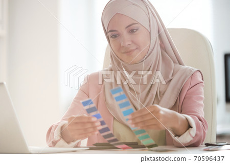 Young pretty Muslim female designer comparing two color palettes at work 70596437