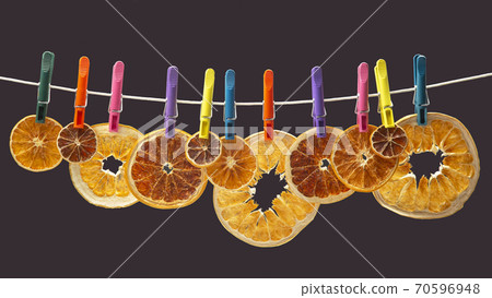 dried pieces of different citrus fruits hang on colored clothespins on a gray background dried pieces of different citrus fruits hang on colored clothespins on a gray background 70596948
