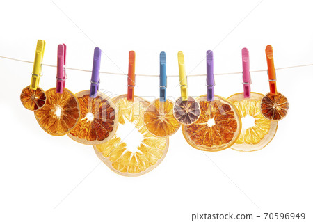 dried pieces of different citrus fruits hang on colored clothespins on white background 70596949