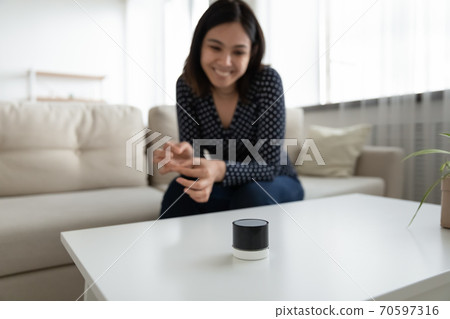 Happy asian woman listen to music on smart speaker 70597316