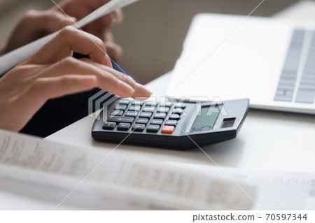 Close up of woman calculate finances expenses on machine 70597344