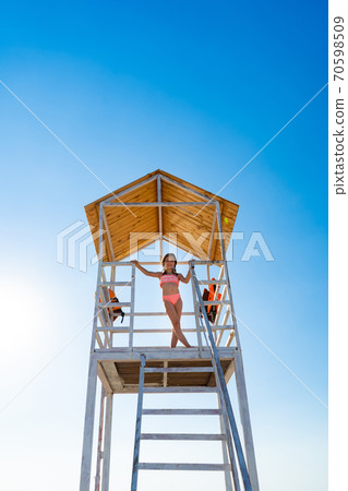 teenage girl stands on lifeguard tower on beach teenage girl stands on lifeguard tower on beach 70598509
