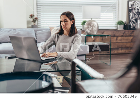 Woman working on laptop while sitting on floor at home. 70603349