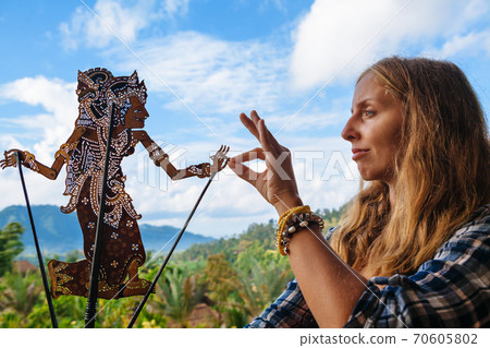 Woman holds in hand traditional Indonesian shadow puppet - Wayang Kulit Woman holds in hand traditional Indonesian shadow puppet - Wayang Kulit 70605802