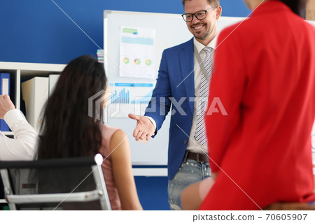 Businessman in jacket and glasses at conference in front of audience of colleagues in office portrait 70605907