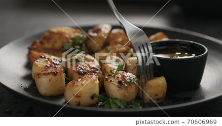 eat roasted scallops with baked potatoes on black plate 70606969
