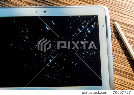 Water spilled onto the tablet, Drops of water on tablet screen Water spilled onto the tablet, Drops of water on tablet screen 70607737