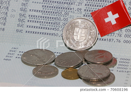 Heap of Swiss franc coin money and mini Switzerland flag on the book bank. Heap of Swiss franc coin money and mini Switzerland flag on the book bank. 70608196