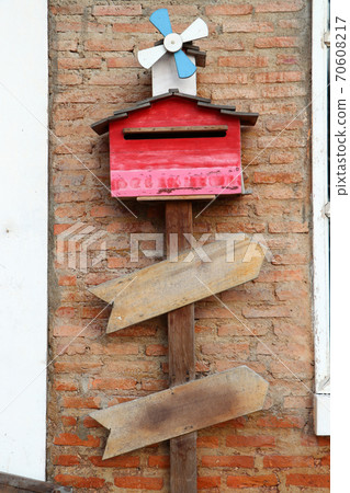 Red wooden letterbox under the small wind turbine on the brick wall. 70608217