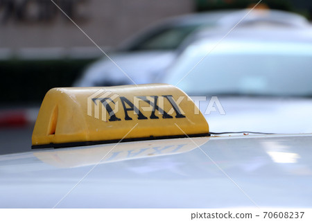 Taxi light sign or cab sign in yellow color with black text on the car roof at the street. 70608237