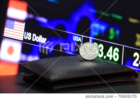 A quarter of US Dollar coins on obverse (USD) on black wallet on black floor with digital board 70608270