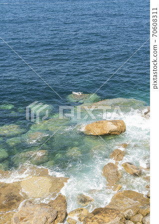 Ocean coast. Clear water. Calm waves crash against stones on a quiet sunny day. Ocean coast. Clear water. Calm waves crash against stones on a quiet sunny day. 70608311