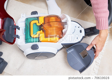 Household appliances service. Woman takes out container of dust from vacuum cleaner Household appliances service. Woman takes out container of dust from vacuum cleaner 70610028