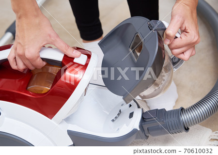 woman take out container of dust from vacuum cleaner woman take out container of dust from vacuum cleaner 70610032