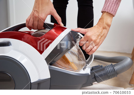 woman take out container of dust from vacuum cleaner woman take out container of dust from vacuum cleaner 70610033