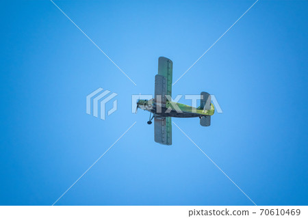 Retro green biplane plane in the blue sky Retro green biplane plane in the blue sky 70610469