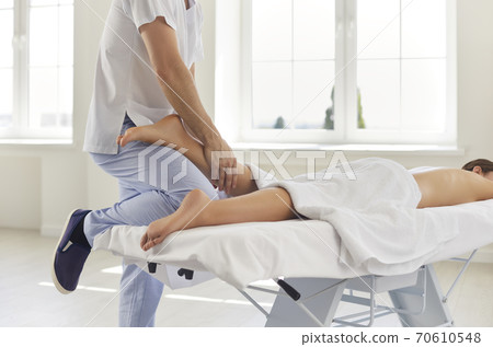 Physiotherapist or professional masseur massaging young woman's calf muscle in health center 70610548