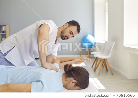 Young doctor specialist curing client's back and shoulders in modern health center 70610560