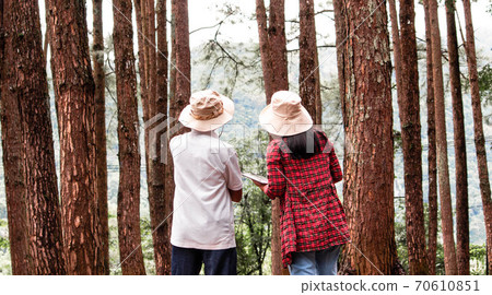 Young woman with her grandfather using digital tablet in pine forest, talking about family organic farm. Modern technology smart farming agriculture and family togetherness concepts. Young woman with her grandfather using digital tablet in pine forest, talking about family organic farm. Modern technology smart farming agriculture and family togetherness concepts. 70610851