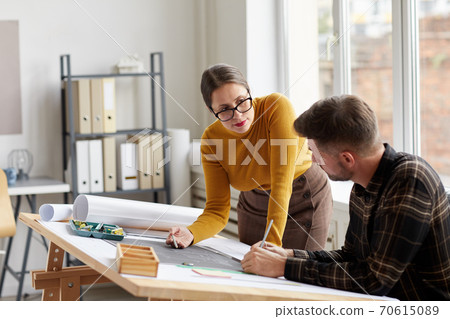 Two Architects Discussing Plans at Drawing Desk Two Architects Discussing Plans at Drawing Desk 70615089