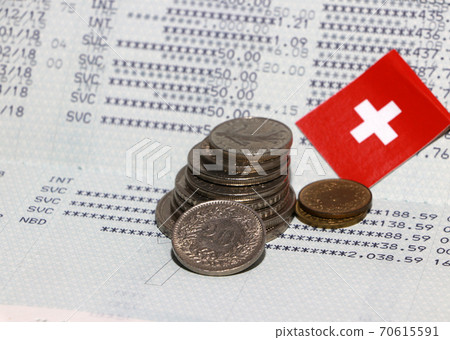 Heap of Swiss franc coin money and mini Switzerland flag on the book bank. 70615591