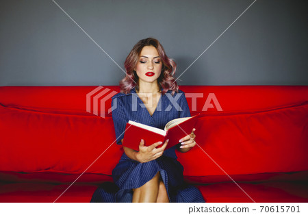Woman reading book on couch 70615701